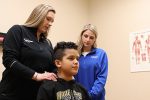 Kara Conroy watches as her internship instructor Brittany Overman Ramirez demonstrates chiropractic care on a young boy.