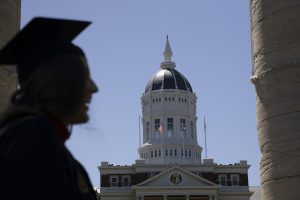 A photo of a graduate's silhouette with Jesse Hall in the background. 