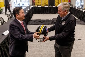 A photo of President Choi presenting a Mizzou Football helmet to Governor Parson