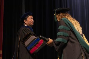 A photo of President Choi shaking hands with a graduate at commencement.
