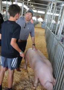 A photo of President Choi talking with a young exhibitor at the Swine Barn.