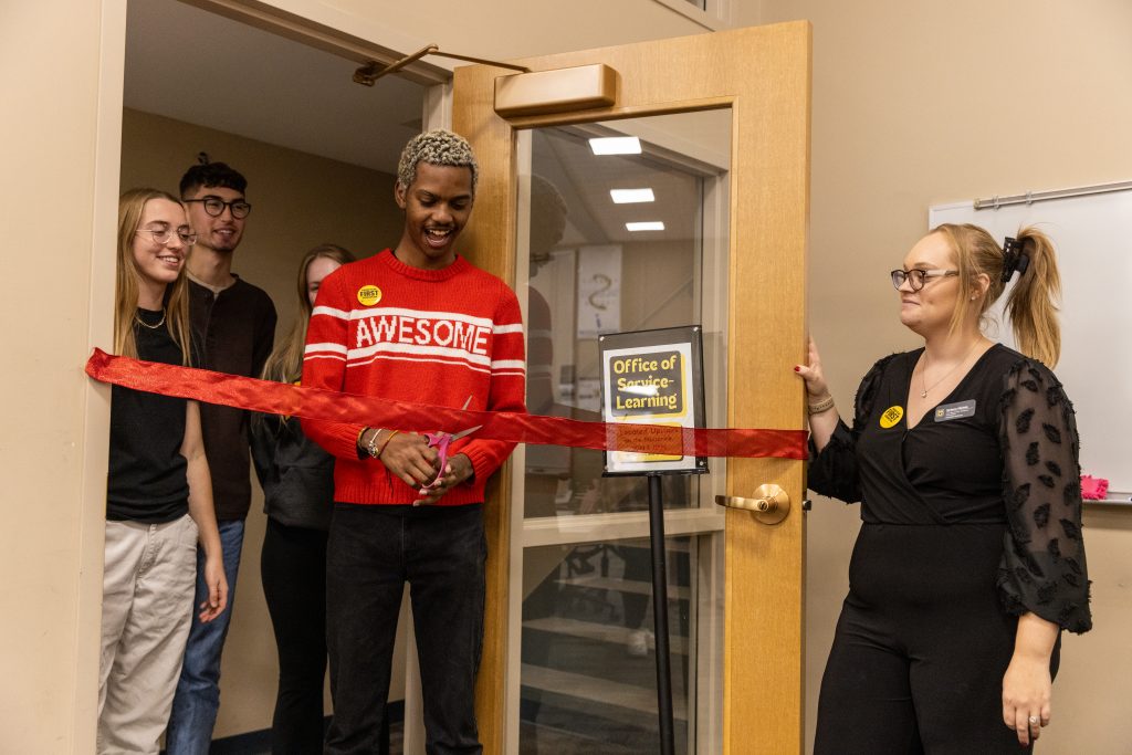 A photo of Eugene Moses, junior communications major, cutting the ribbon for the Office for First Generation Initiatives in the Student Success Center.