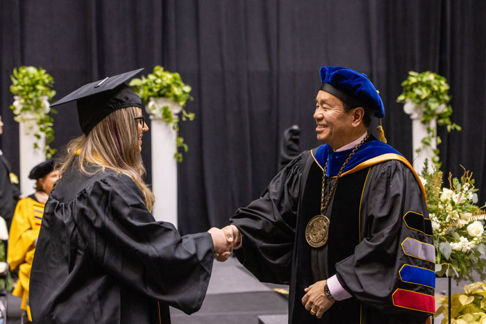 President Choi congratulating a graduate in a commencement ceremony
