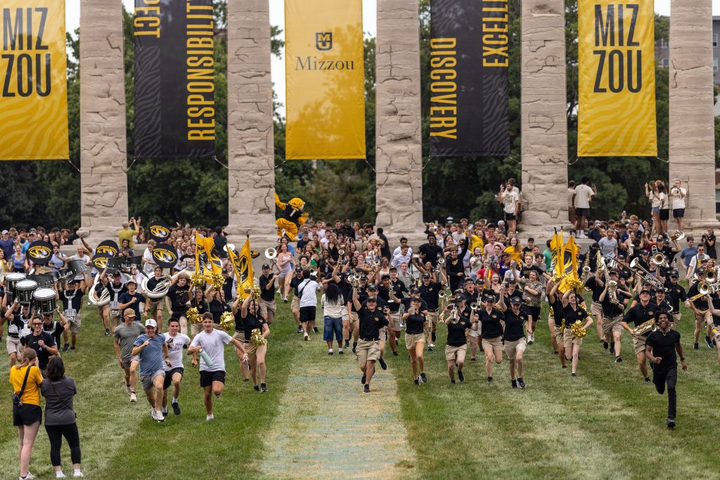 Mizzou students running through the Columns at Tiger Walk.